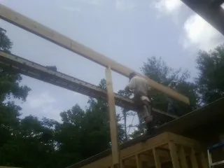 Carpenter setting a ridge beam over a new addition frame — Ice Dam Removal by Roofing Brothers in Waller