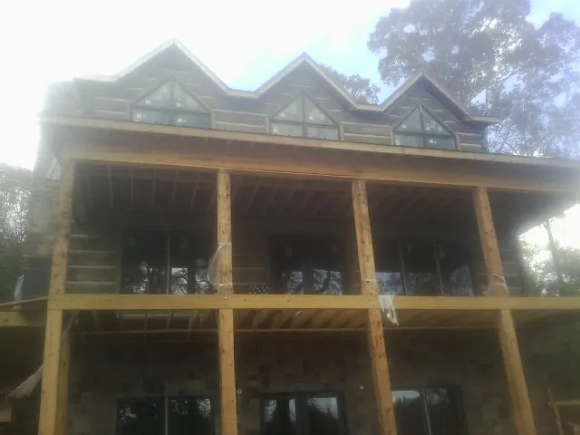 Dormers and porch framing on a large log home under construction — Roof Coating work by our crew in Waller