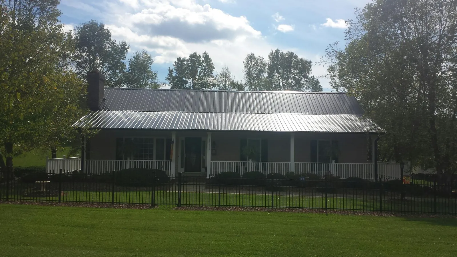 Gray metal roof on a brick ranch with a full width front porch — Gutter Guard Installation work by our crew in Waller