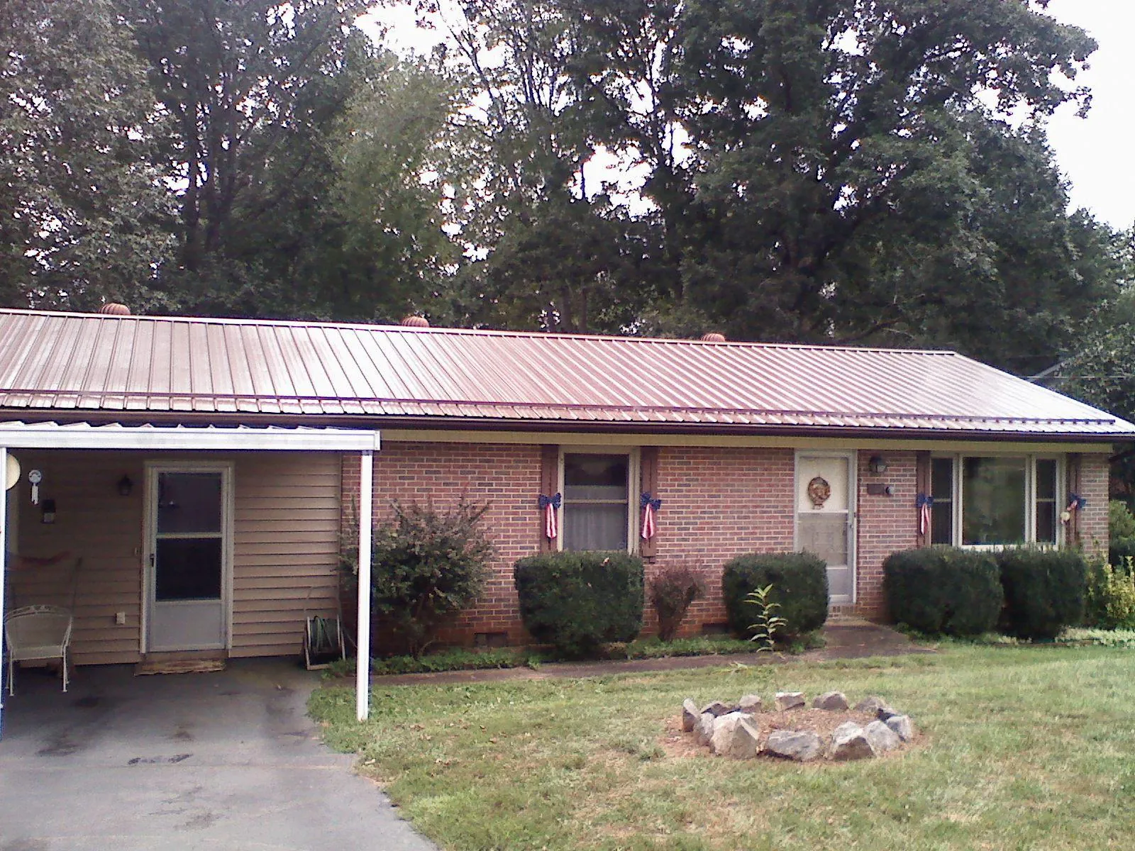 Bronze metal roof and carport on a brick ranch home — Roof Repair work by our crew in Waller