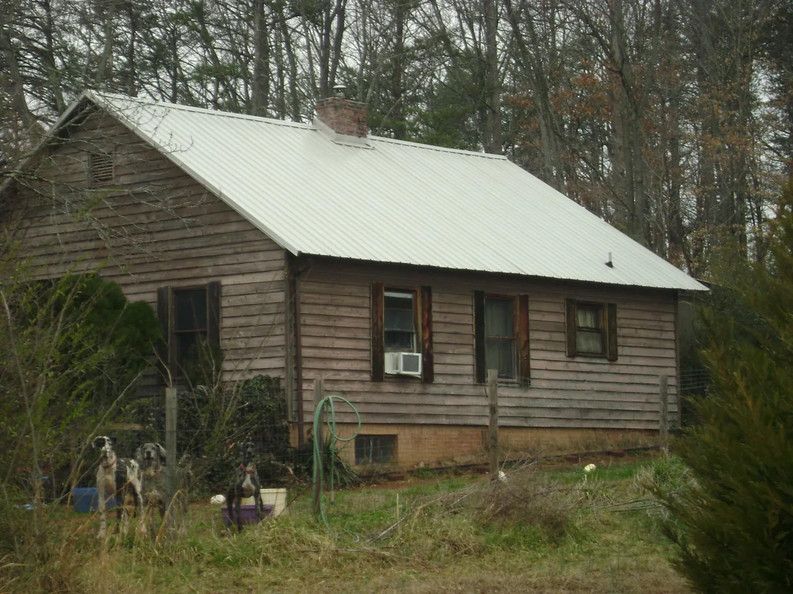 White metal roof on an old wood sided farmhouse, from a Metal Roof Installation job in Waller